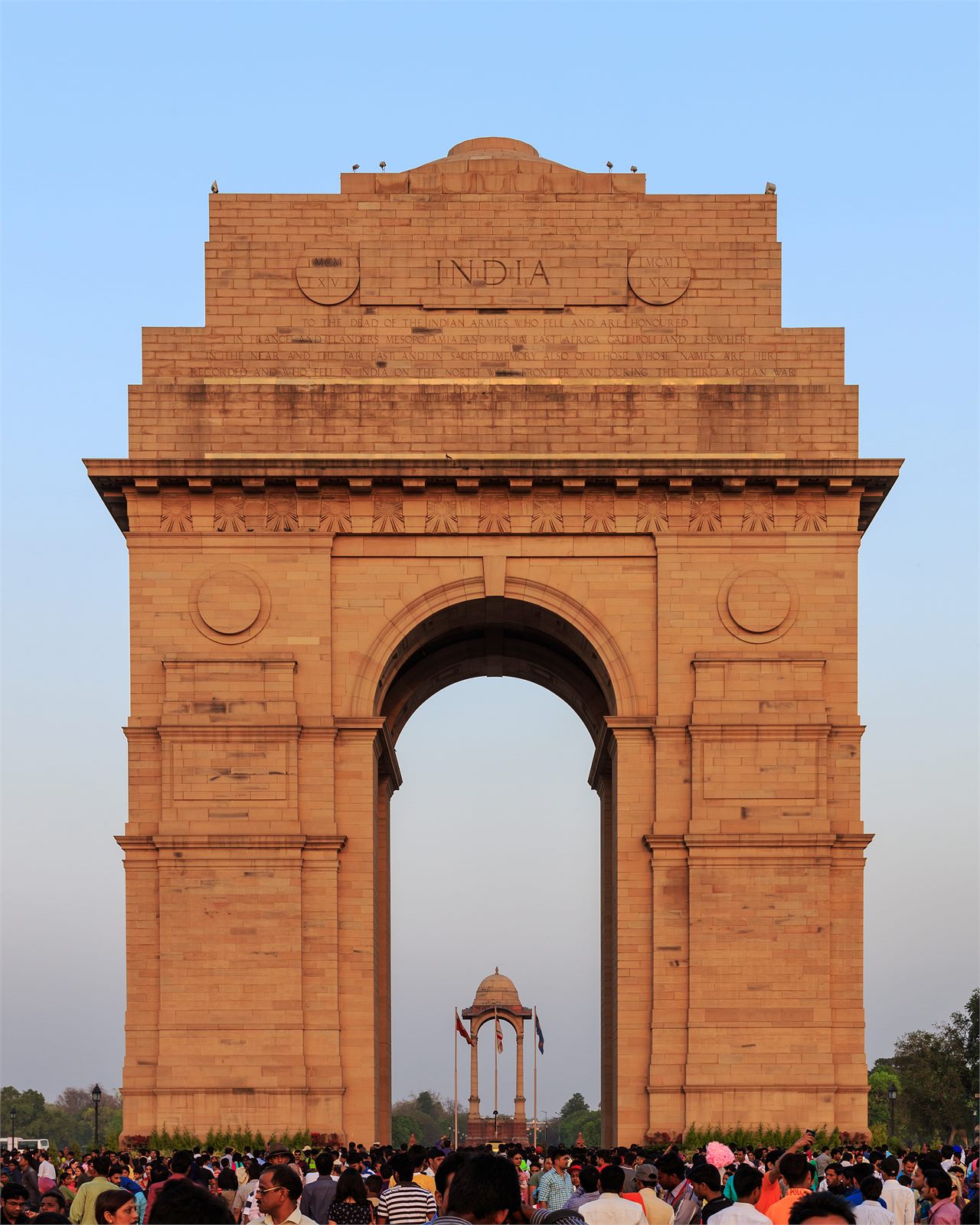 Das India Gate in Neu-Delhi im Abendlicht, davor eine Menschenmenge.